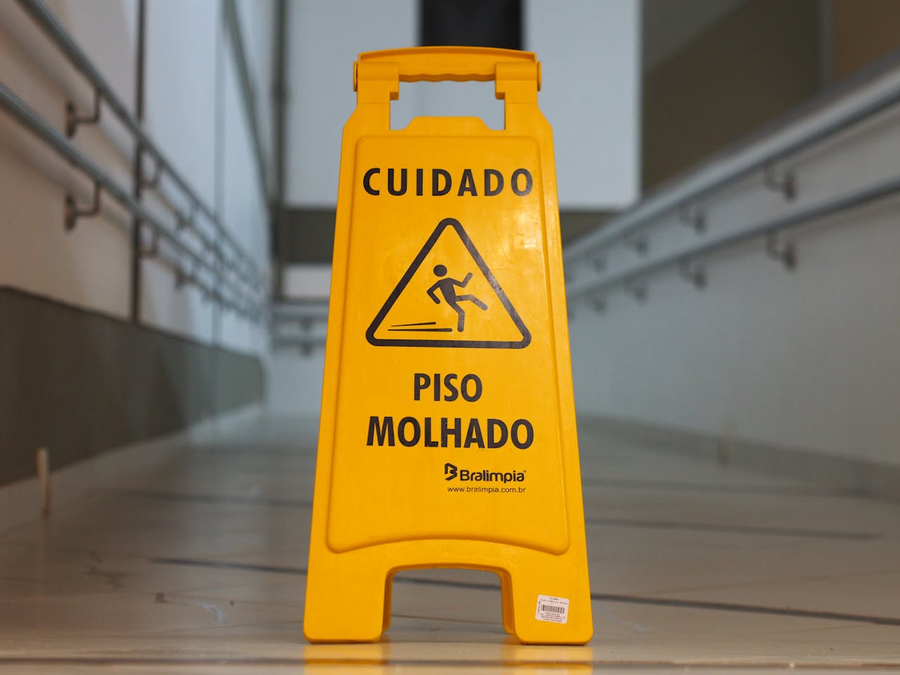 What’s Included in Commercial Cleaning Services? Bright yellow caution sign signals wet floor in a corridor with tiled flooring.