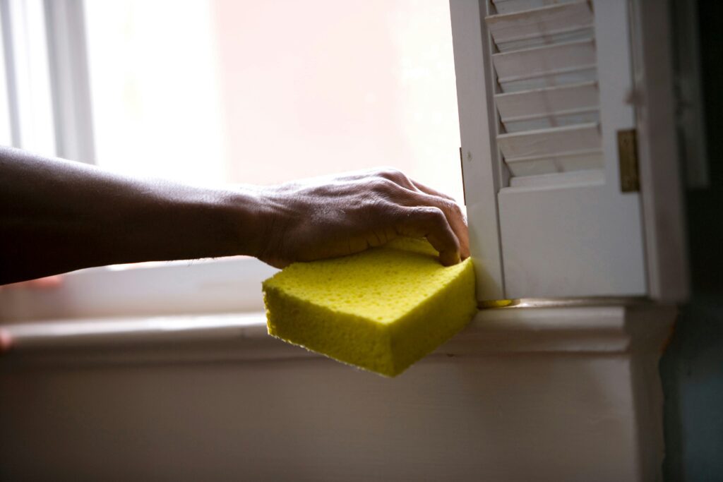 Hand wiping kitchen surface with yellow sponge during residential cleaning