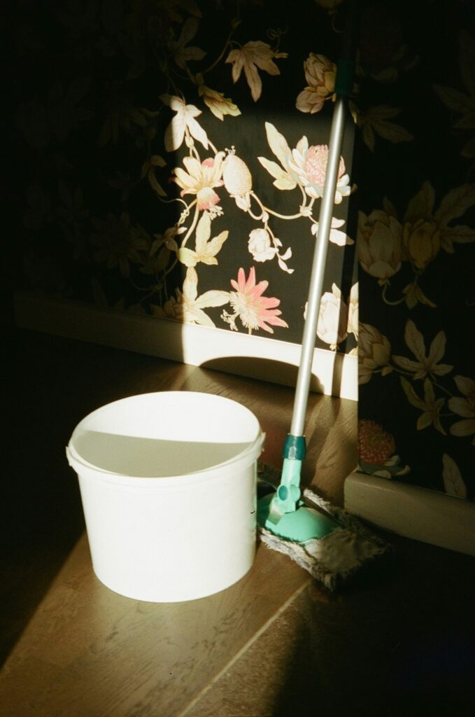 Cleaner in green apron wiping down kitchen countertop surface