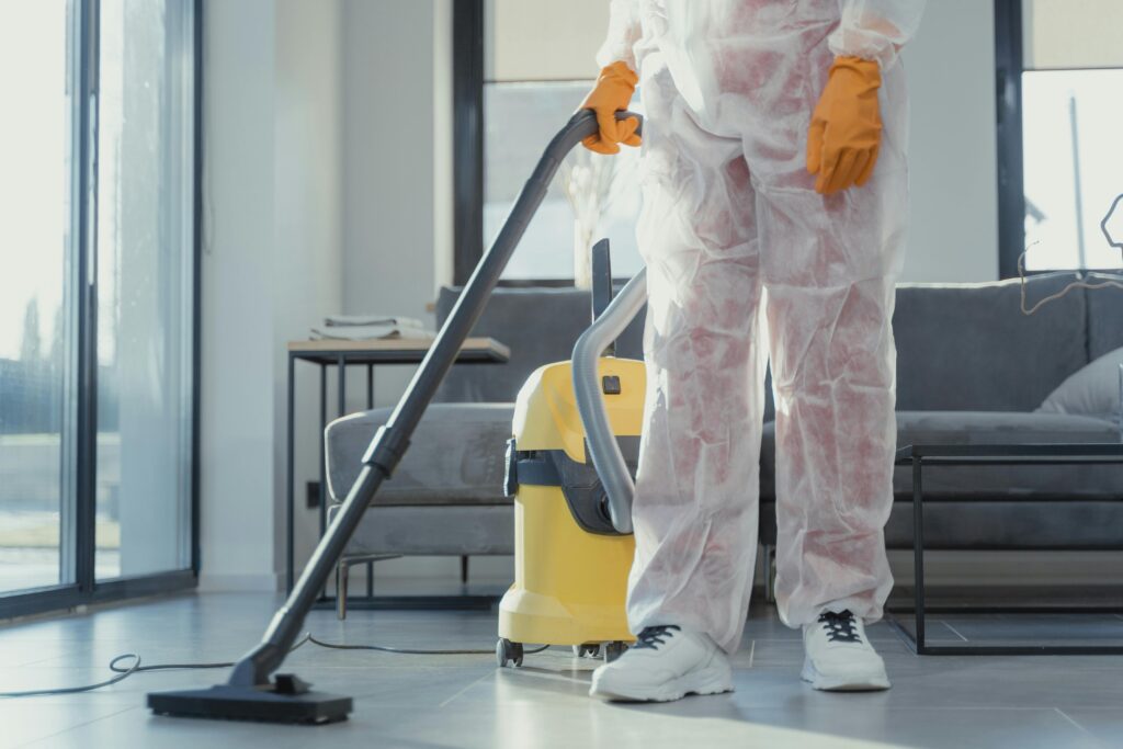 Cleaning professional in white coveralls vacuuming commercial floor