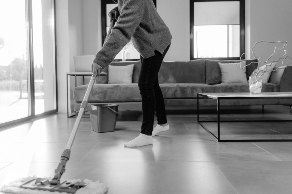 Professional cleaner mopping living room floor during turnover cleaning