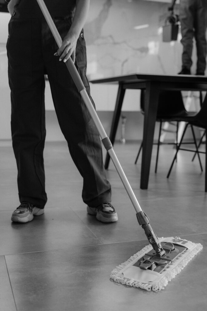 Professional cleaner mopping hardwood floor in home