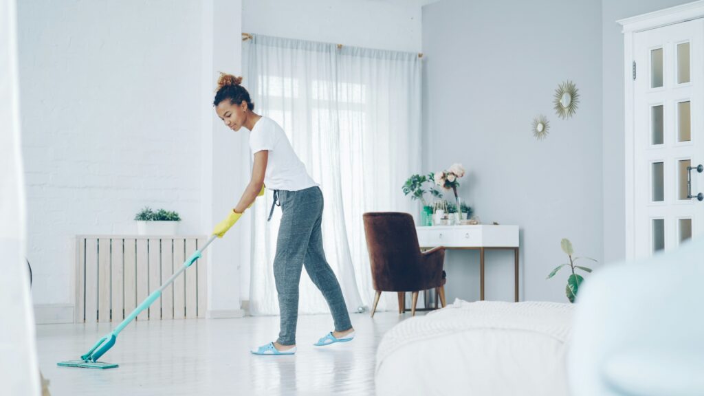 Woman cleaning and wiping surfaces near large window with natural light